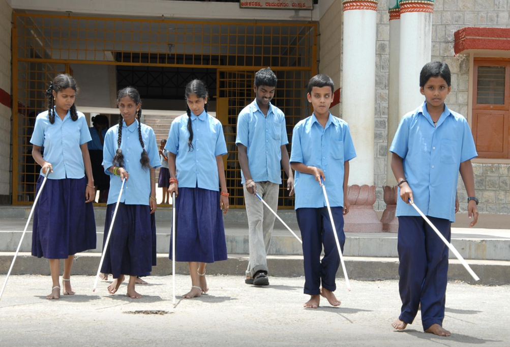 Blind Children walking with thier stick. All wearing blue shirts